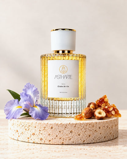 Parfum Éclate de Vie Astharte 100 ml pe piatră de travertin, cu iris, alune caramelizate și praline